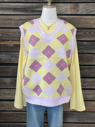 Mannequin wearing a yellow and purple checkered sweater against a wooden background