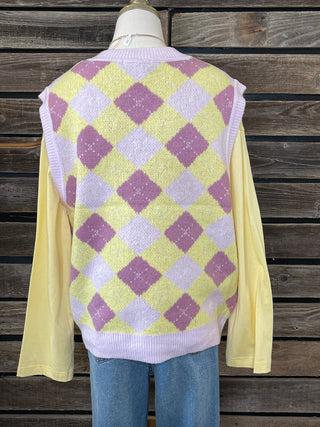 mannequin wearing a yellow and purple checkered sweater over a yellow shirt against a wooden background