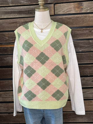 Green and pink checkered sweater vest on a mannequin against a wooden background