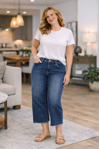 Woman wearing a white t-shirt and blue jeans standing in a living room.